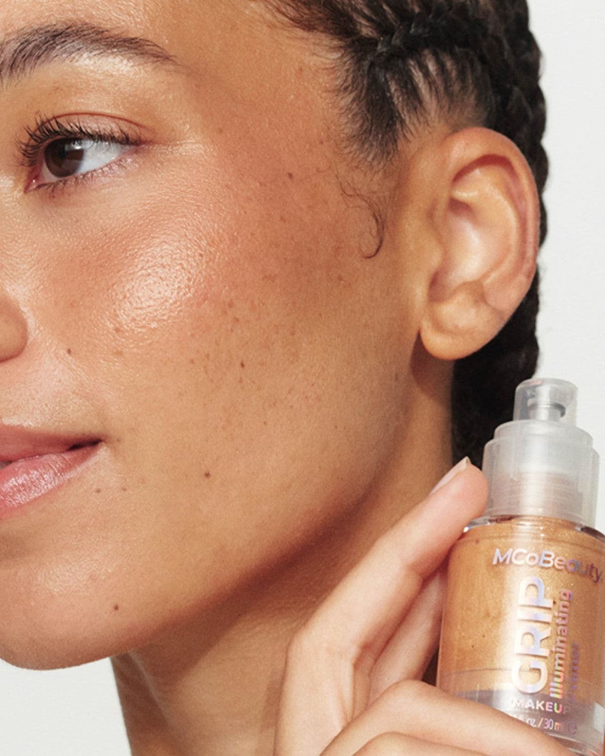 Close-up of a model applying MCoBeauty Grip Illuminating Primer to her cheek