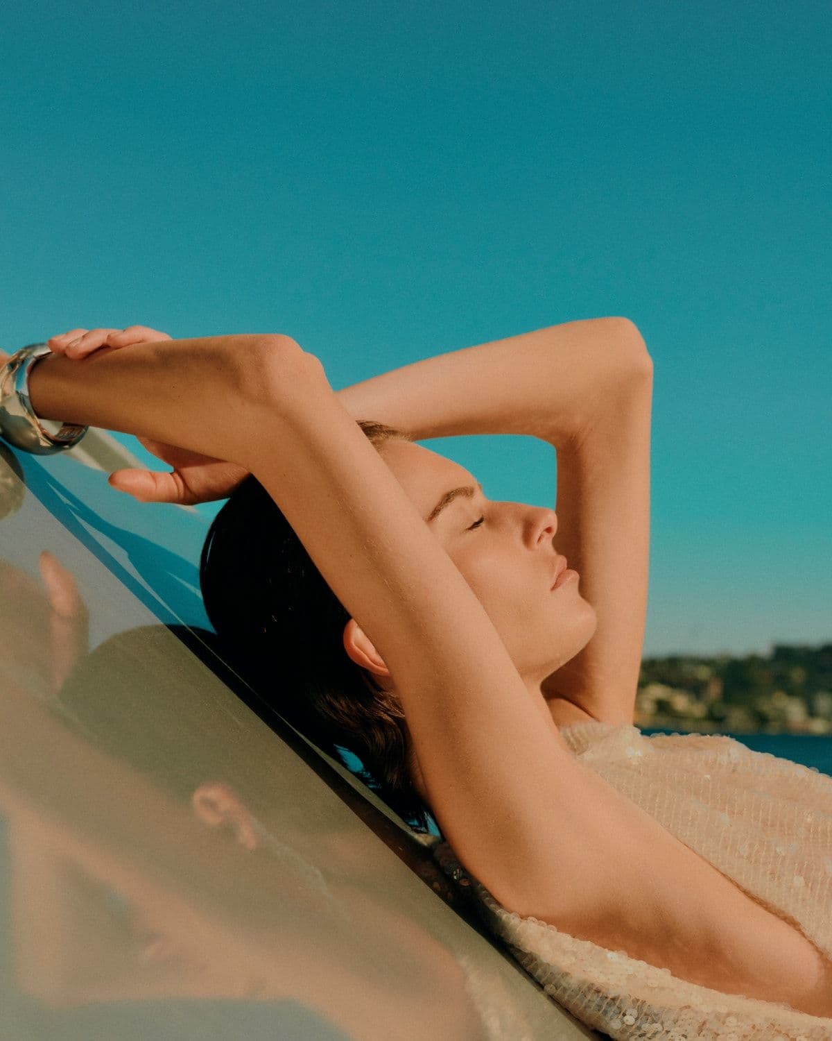 Model in sequinned gown reclining against yacht railing, portrait crop, Pre-Fall '26 campaign