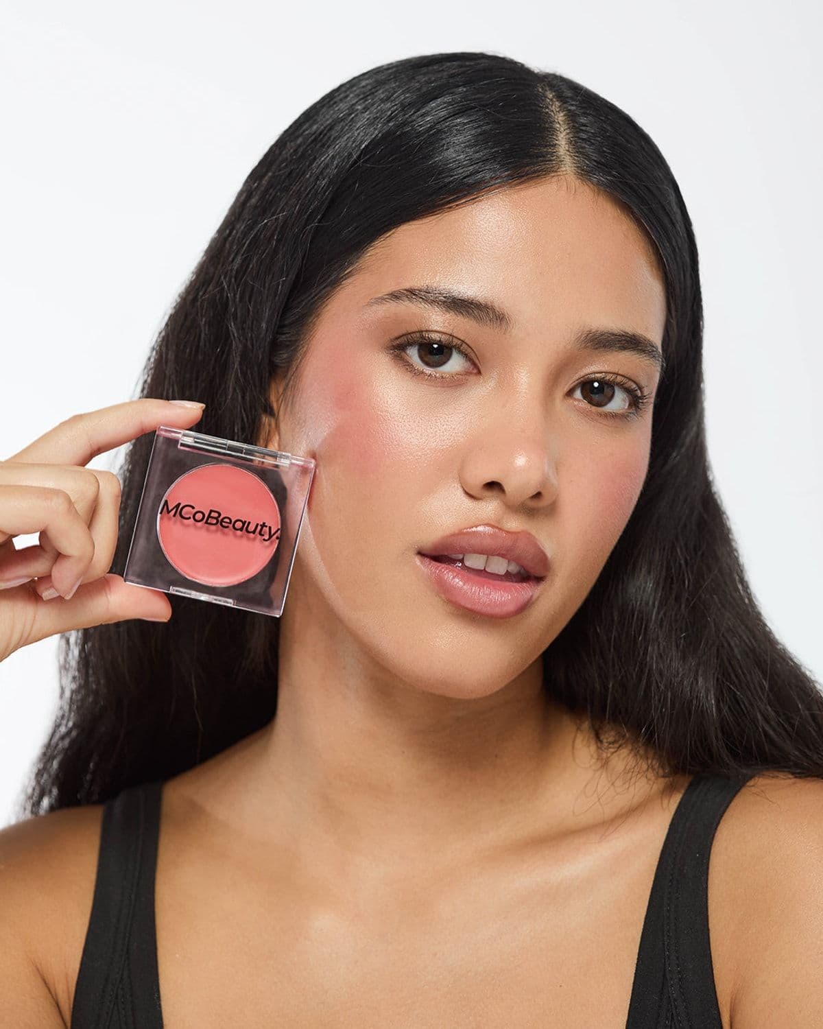Model holding an MCoBeauty blush compact to her cheek in an editorial beauty close-up
