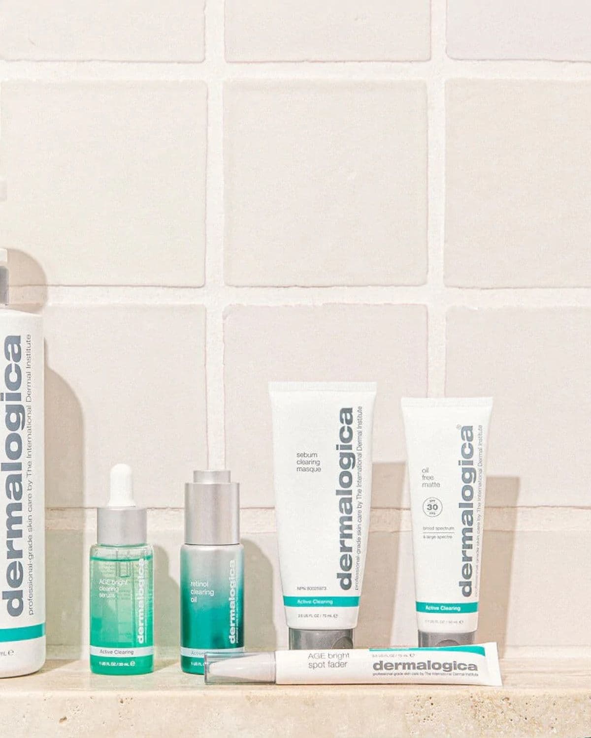 Editorial product flat-lay of the Active Clearing range - clearing skin wash, AGE bright serum, retinol clearing oil, sebum clearing masque, oil-free matte SPF and spot fader - arranged on a cream tiled shelf