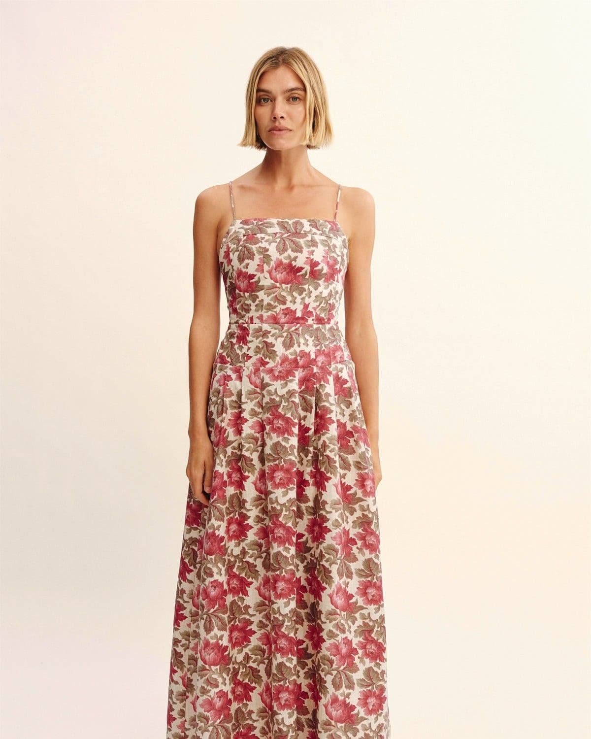 Model wearing an antique-rose floral print linen maxi dress with square neckline, studio shot on cream background