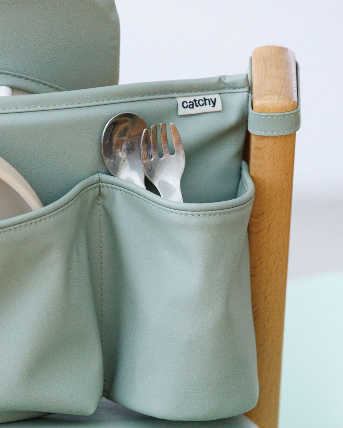 Macro shot of cutlery tucked into the side pocket of the Catchy caddy on a high chair