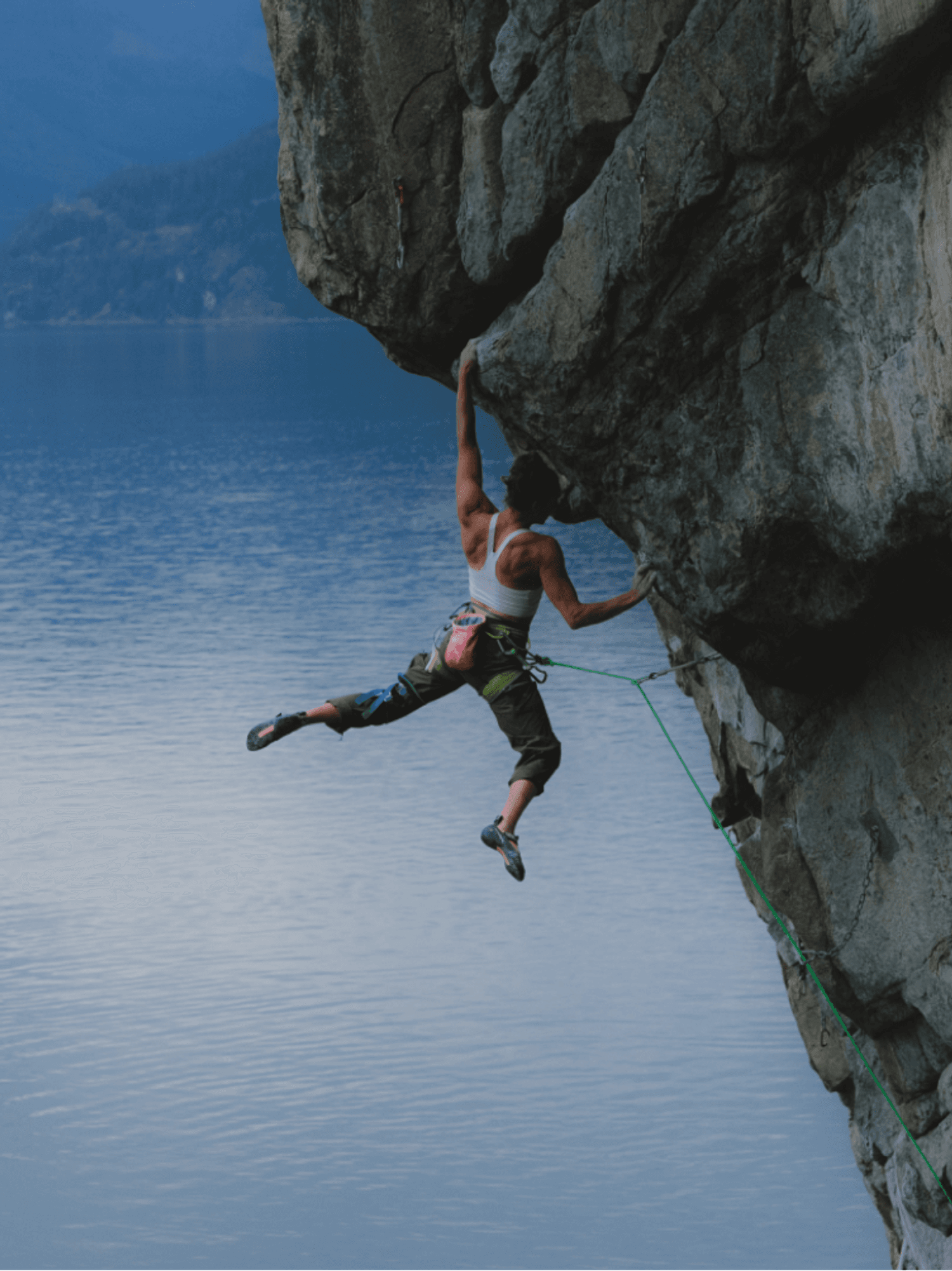 Climber hanging from an overhang above a still lake at dusk, from the official Arc'teryx campaign