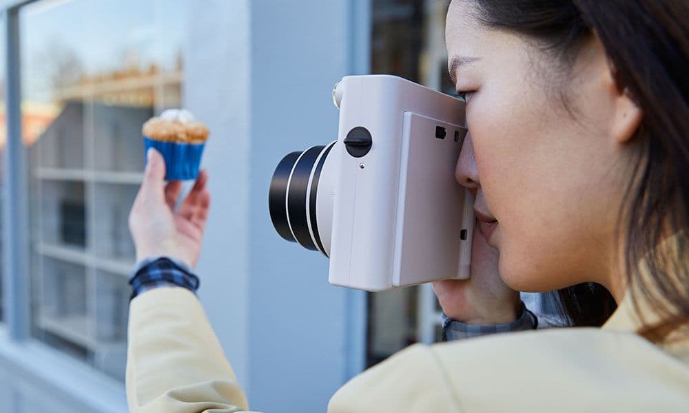 Person shooting an Instax SQUARE SQ1 camera on the street