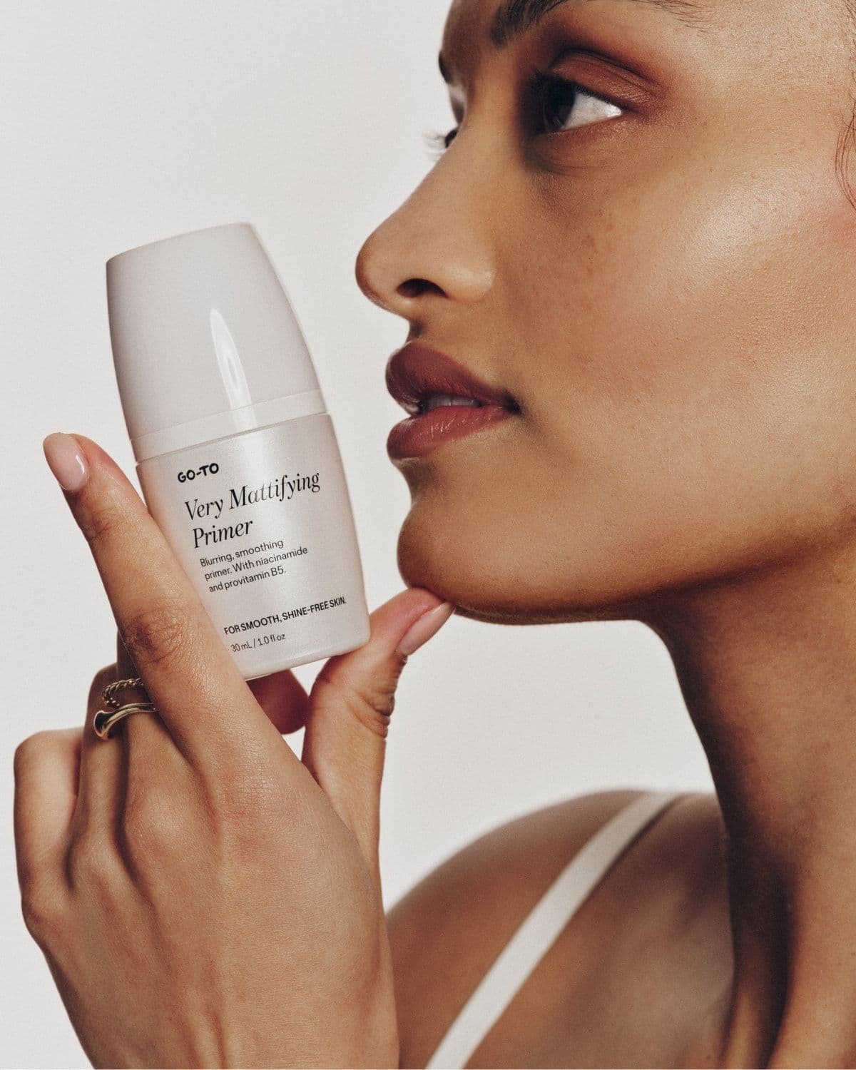 Model profile shot holding Very Mattifying Primer near her chin
