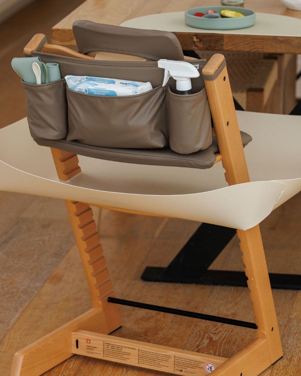 Catchy Chaos-Control Caddy attached to a Stokke Tripp Trapp high chair on a wooden breakfast table with fruit bowl
