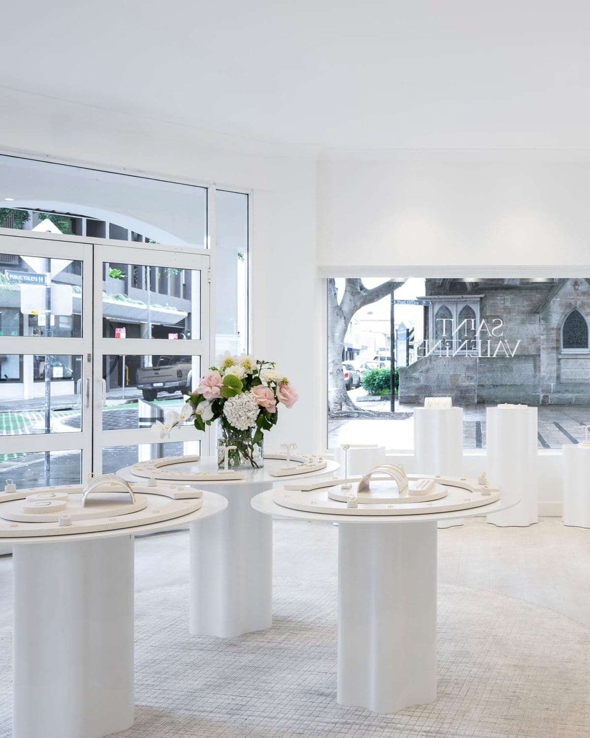 Interior of the Saint Valentine Manly boutique with white display tables and round mirrors