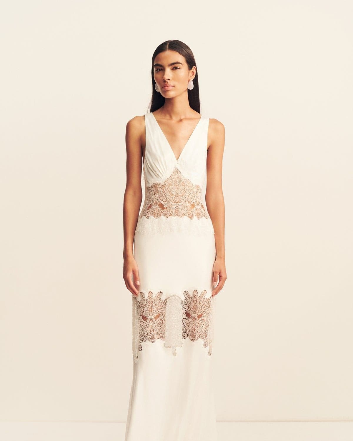 Model in the Stratus Plunged Lace Panelled Maxi Dress (ivory), front-facing studio shot with sheer lace waist and hem panels